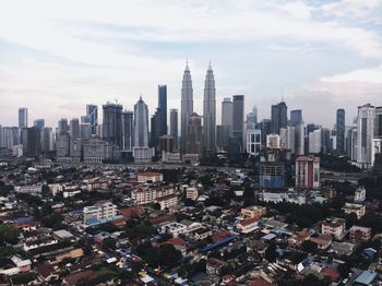 Aerial view of buildings in city against cloudy sky