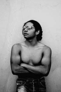 Young man looking away while standing against wall