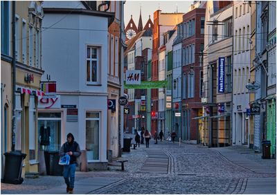 People walking on street amidst buildings in city