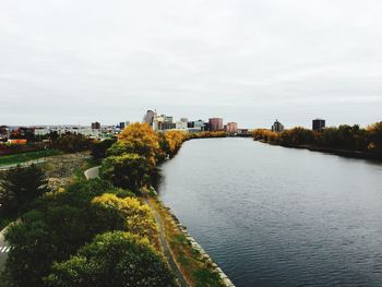 Scenic view of river with trees and buildings in background