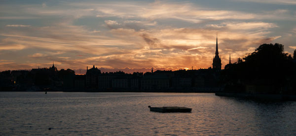 Silhouette of buildings in city at sunset