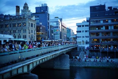 People on bridge over river in city