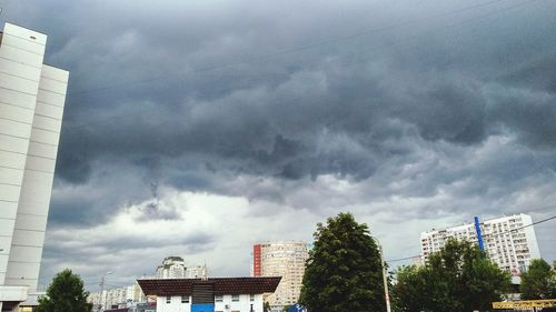 Low angle view of buildings in city against cloudy sky