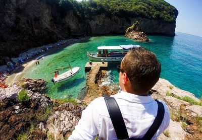 People on boat in sea against rock formation