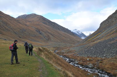 Rear view of people walking on mountain against sky