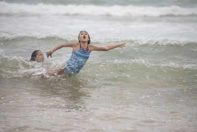 Happy sisters playing together in sea