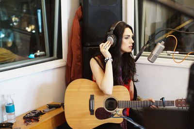 Young woman playing acoustic guitar at a recording studio