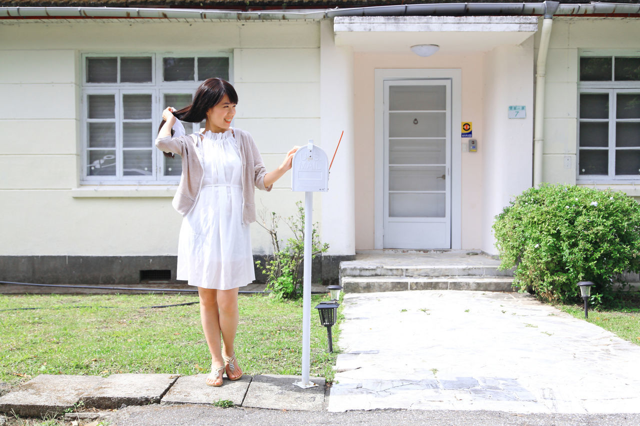 full length, young adult, lifestyles, building exterior, casual clothing, architecture, built structure, standing, leisure activity, person, young women, side view, house, front view, holding, day, grass