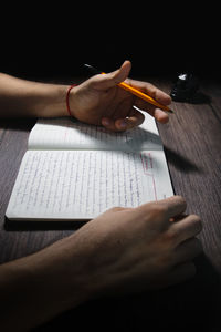 High angle view of hand holding book on table