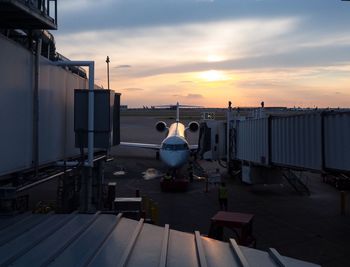 Airplane on airport runway against sky during sunset
