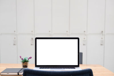 Laptop or notebook with blank screen on wood table with house or office modern