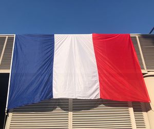 Low angle view of flag against buildings against clear blue sky