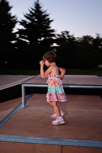 Side view of girl on ramp at skateboard park during sunset