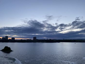 Scenic view of sea and buildings against sky at sunset