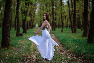 Woman with arms raised on field in forest