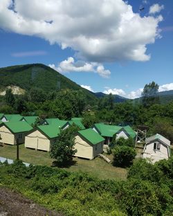 Houses by trees and buildings against sky