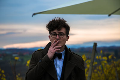 Portrait of young woman standing on field against sky