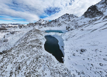 Three mountain frozen turquoise lakes in the snowy mountains, top view from a drone