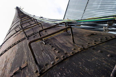 Power cables mounted on tall tower against sky