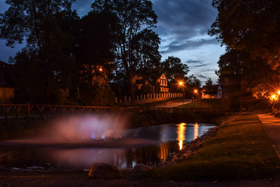 Illuminated bridge over river against sky at night