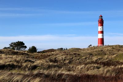 Lighthouse on landscape against blue sky