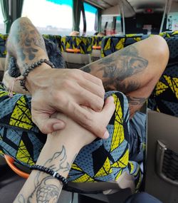 Cropped image of couple holding hands in bus