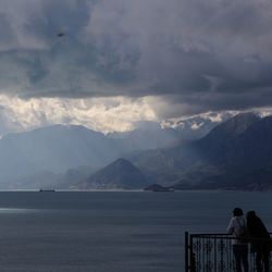 Rear view of people looking at mountains against sky