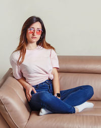 Portrait of young woman wearing sunglasses sitting at home