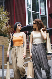 Lesbian couple holding shopping bags walking on steps outdoors