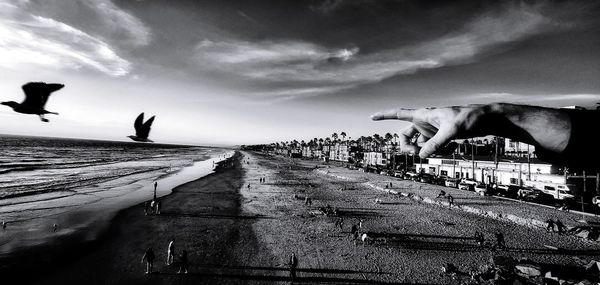 People on beach against sky in city