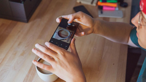 Teenager boy photographing coffee cup through smart phone