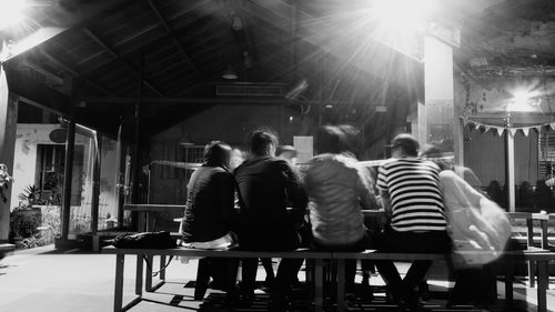 Rear view of people sitting in illuminated building