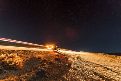 Light trails on road against sky at night