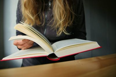 Midsection of woman reading book on table