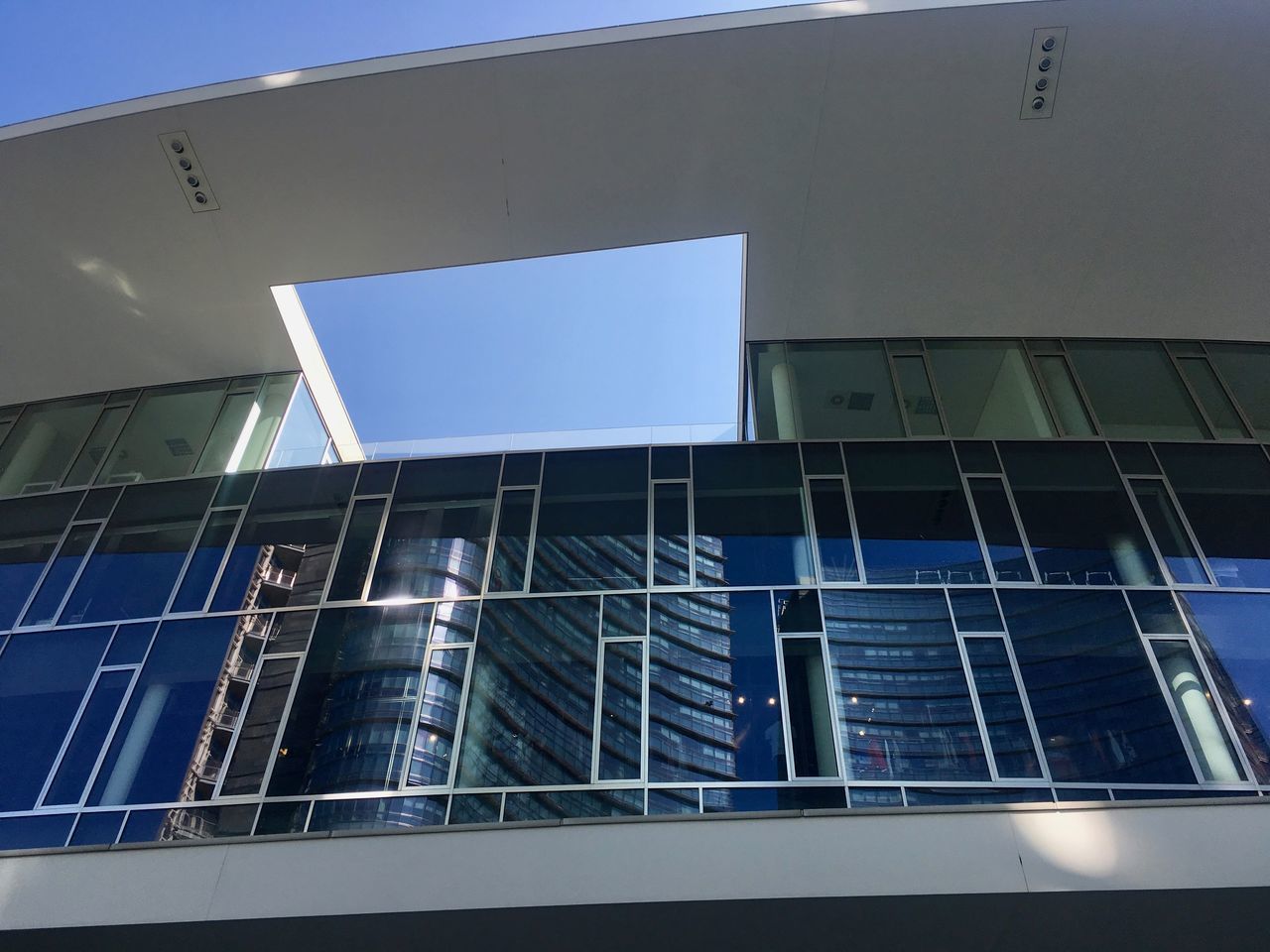 LOW ANGLE VIEW OF MODERN GLASS BUILDING AGAINST CLEAR SKY