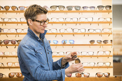 Mature woman holding sunglasses standing in store