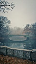 Bridge over river against sky during foggy weather