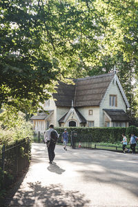 Full length of woman walking by building against trees