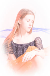 Young woman looking away while sitting on floor