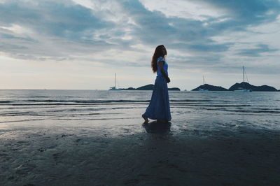 Woman standing on beach against sky