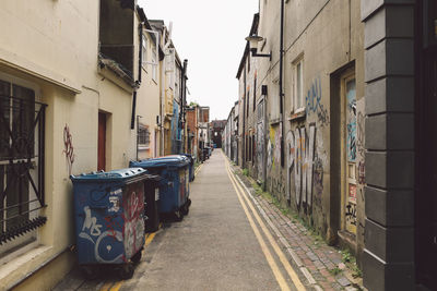 Garbage bins in alley amidst buildings at town