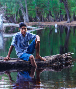 Young man sitting by lake