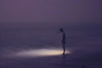 Silhouette of man standing on beach at night