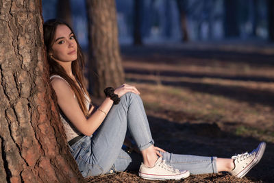 Young woman sitting on tree trunk