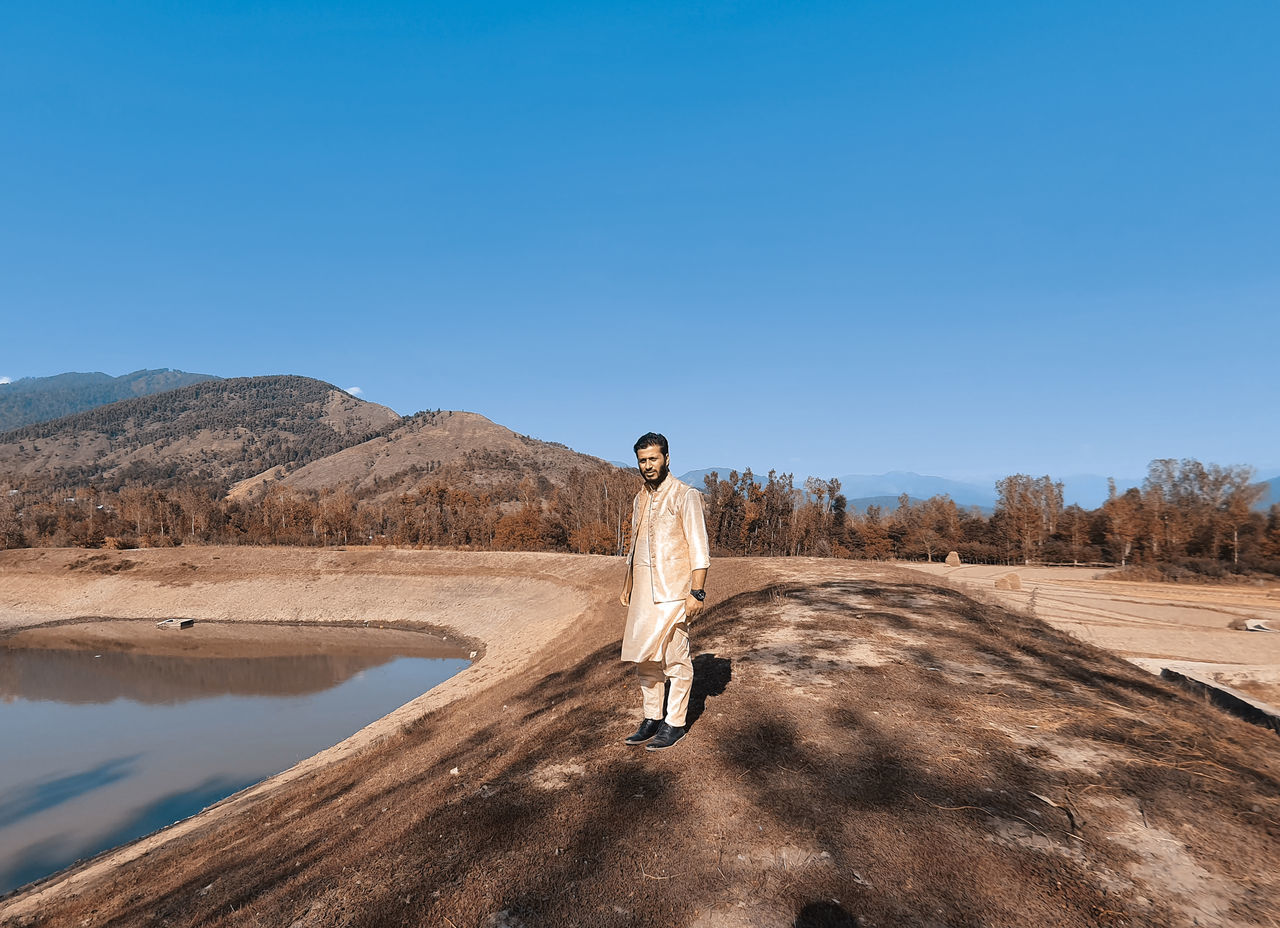 MAN STANDING ON ROCK AGAINST SKY