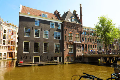 Buildings by canal against sky in city