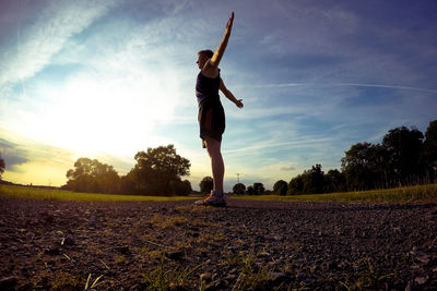 Full length of man exercising on road during sunset