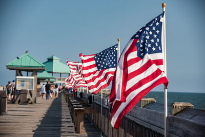 Flags by sea against clear blue sky