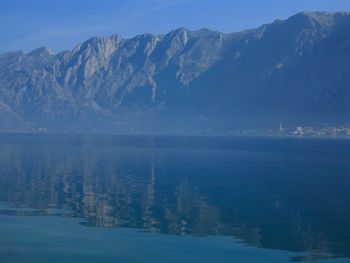 Scenic view of lake and snowcapped mountains against blue sky