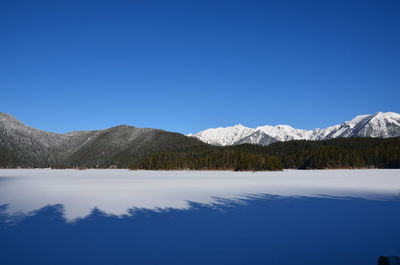 Scenic view of lake and mountains against clear blue sky